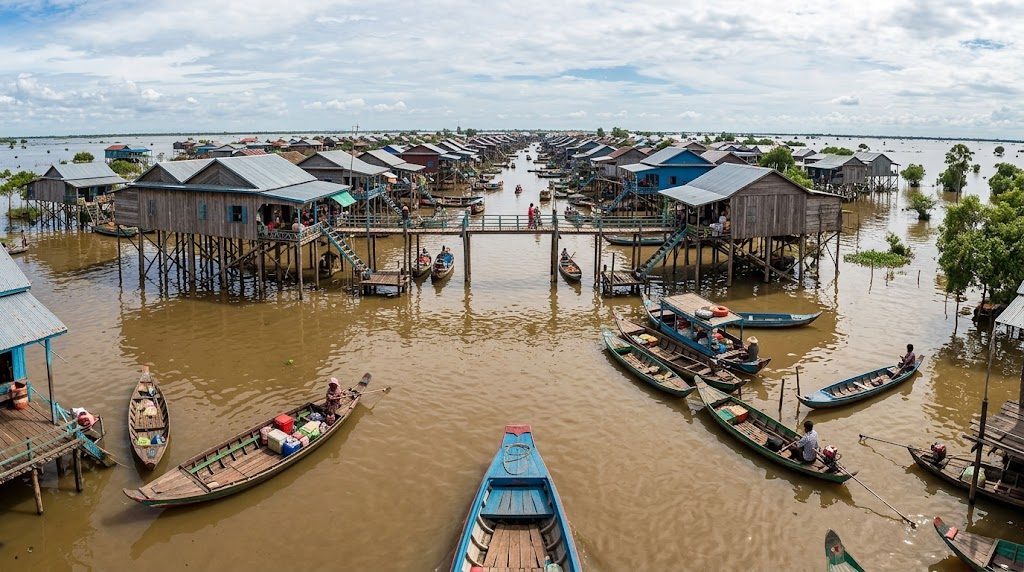 Houten paalwoningen torenen hoog uit boven het water in de drijvende dorpen van het Tonlé Sap meer